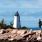 two people walking on a rocky beach with Crisp Point Light in the background